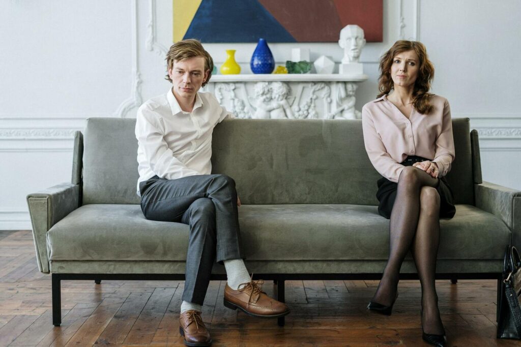 unhappy couple sitting apart on a couch for post about support after separation
